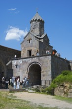 Popular chapel with tower and group of visitors under blue sky, Tatev monastery, Armenian Apostolic