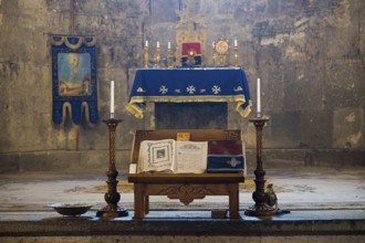 Religious altar in a church with decorated candelabra, lit candles and an opened book, Tatev