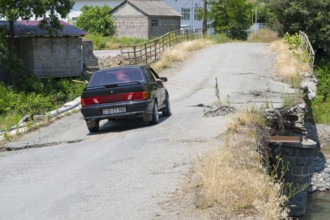 A black car crosses a dilapidated bridge in rural area, Lada Samara drives on bridge over the Debed