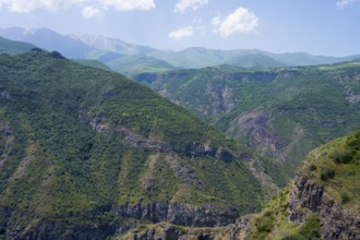 Green mountains with scattered clouds in the sky, peaceful and natural surroundings, view from