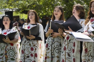 Women sing in a choir, elegantly dressed in painted robes, cheerful atmosphere, choir at Tatev