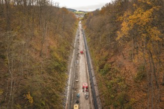 An autumn construction site in a wooded area, seen from a bird's eye view, with diverse autumn