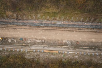 Aerial view of a construction site in an autumn area with construction along a path, construction