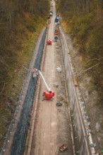 Construction work on a path in a wooded area with machines and a lift, construction of the Hermann