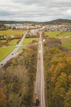 Construction site along a road in an autumn landscape near a village seen from the air,