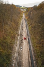 View of a construction site in a wooded autumn landscape with construction equipment and excavation