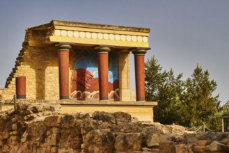 Part of the ancient palace of Knossos with well-preserved fresco and red columns surrounded by