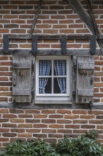 Rustic window with blue curtains and wooden shutters on the brick wall, Münsterland, North
