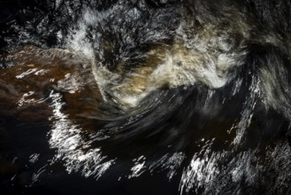 Stream flow with dark water, reflections and turbulences, long exposure, Sweden