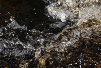 Stream flow with dark water, reflections of light and turbulence, Sweden