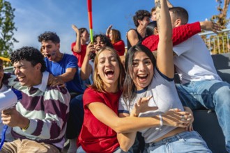 Cheerful young friends sitting in stadium stands, actively cheering and celebrating, enjoying a