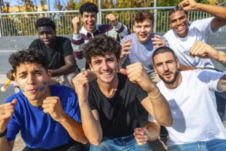 Enthusiastic young diverse male friends sitting on grandstand steps watching a sports event,