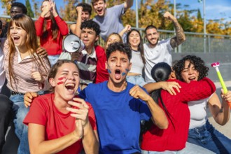 Group of diverse young sports fans celebrating and cheering loudly, showing strong emotion with