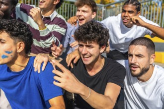 Diverse young male friends are excitedly cheering on their team from stadium stands, showing