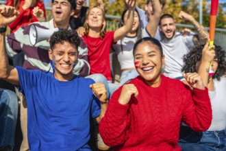 Diverse group of young sports fans cheering with painted faces and team colors in a stadium,