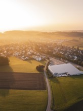 Aerial view of a village with fields at sunset and a modern building, Gechingen, Germany