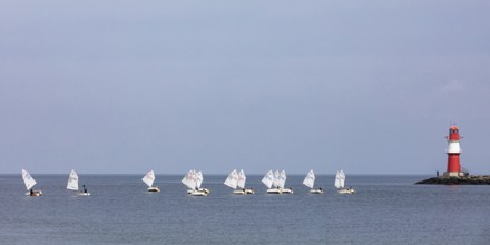 Sailing course with Optimist class sailboats, a sailing dinghy and the pier fire in Warnemünde,
