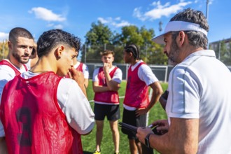 Soccer coach providing instructions and discussing game strategy with a group of young male team