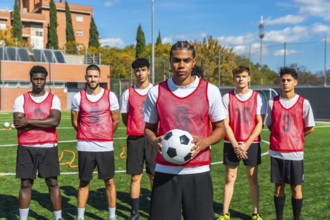 Young men from diverse backgrounds forming a soccer team, standing on a green artificial turf field