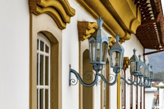 Antique metal lanterns decorating the facade of a historic colonial-style house in the city of Ouro
