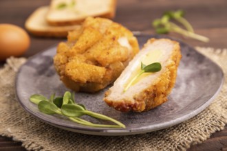 Chicken Schnitzel on gray plate with microgreen on brown wooden background and linen textile. side