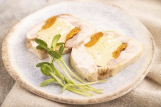 Chicken, egg and dried apricot meatloaf, microgreen on brown concrete background and linen textile.