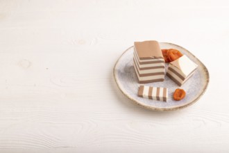 Cocoa and milk jelly with dried apricots on white wooden background, side view, copy space,