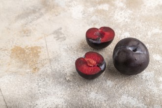 Purple Plum Cut in half on brown concrete background. Side view, copy space. healthy food,