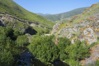A lush valley crossed by a river, surrounded by tall green mountains under a clear sky, Vorotan