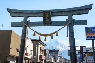 Large torii gate on above a street, street scene, in the back volcano Mt. Fuji, Fujiyoshida,