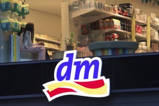 Illuminated logo of a dm drugstore branch at dusk with an insight into the shop, Tauentzienstraße,