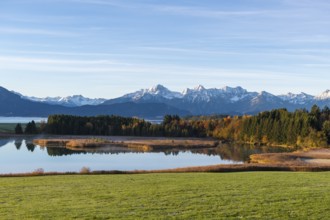 View of a lake surrounded by forests and snow-covered mountains in an autumnal atmosphere,