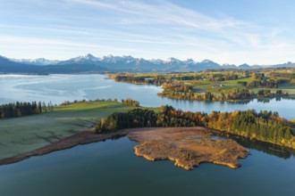 Landscape with clear lake surrounded by autumn forests and alpine scenery on the horizon,