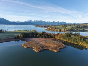 Clear image of a lake surrounded by autumn trees and mountain views, Illasbergsee, Forggensee, near
