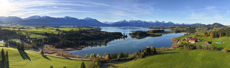 Panoramic view of a green landscape with lake and mountains under a clear sky, Illasbergsee,