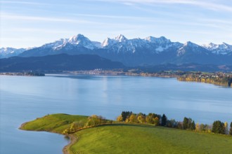 View over quiet lake and rolling hills to the chain of snow-capped alpine mountains in the