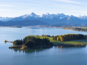 Diverse alpine landscape with a peaceful lake, autumnal wooded hills and snow-capped mountains