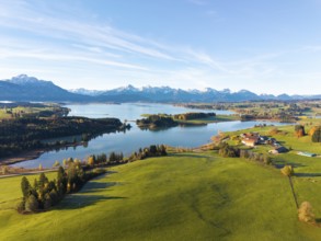 View of a lake surrounded by green hills and mountains under a clear blue sky, Illasbergsee,