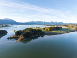 Tranquil landscape with a still lake and autumnal forests in front of an alpine panorama,