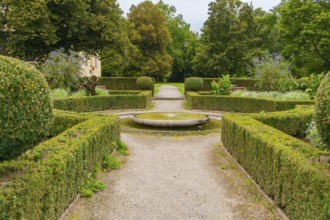 A symmetrical garden with well-kept hedges and a central path leads through the green area, ZFP
