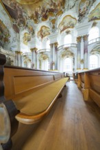 Wooden bench in church interior under artfully decorated baroque frescoes and columns, ZFP