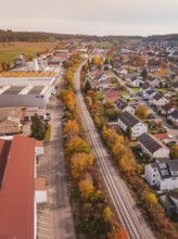 A Hermann Hesse Railway line runs through a town with autumn leaves, surrounded by residential
