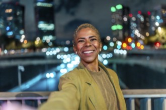 Happy black woman capturing a selfie at an urban bridge, her bright smile and short hair