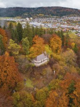 Historic pavilion surrounded by colorful autumn vegetation with a view of the city and hills under