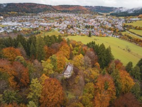 Pavilion in the middle of a colorful autumn forest with a view of a distant city and hills under