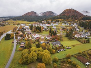 Aerial view of a village surrounded by autumnal hills and clouds of fog, Wehingen, Tuttlingen