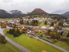 Village nestled in autumnal hills with colorful trees and a curved road, Wehingen, Tuttlingen