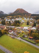 Small village in autumn surroundings with colorful trees and foggy hills in the background,