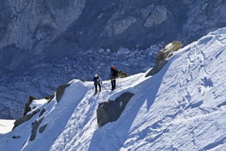 Two ascended mountaineers run across a snow-covered mountain ridge, Aiguille du Midi,
