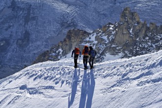 Three ascended mountaineers run across a snow-covered mountain ridge, Aiguille du Midi,